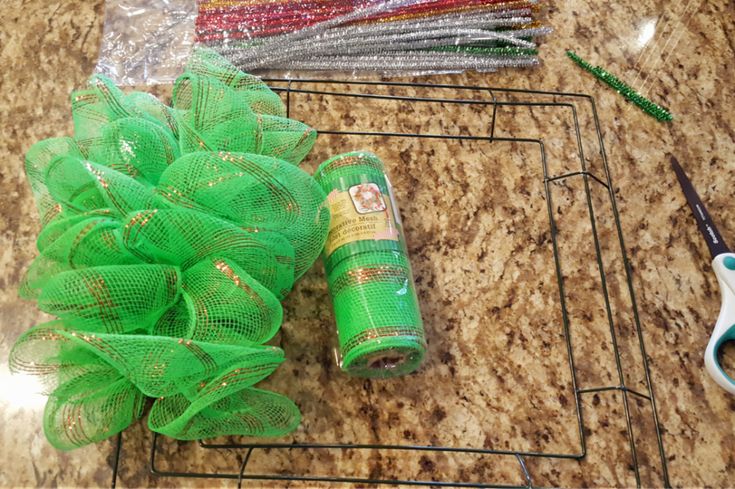 green mesh wreath sitting on top of a counter next to scissors and other crafting supplies