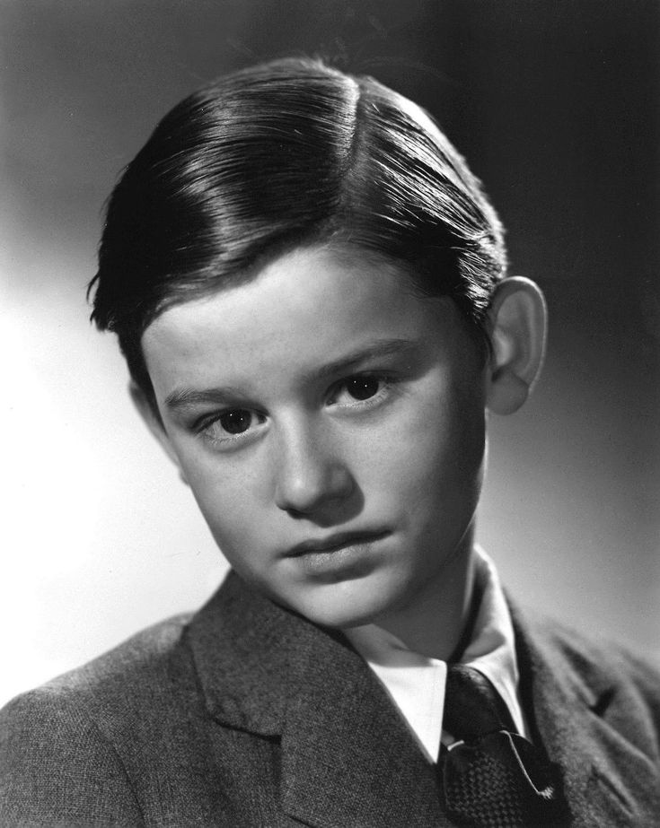 an old black and white photo of a young boy wearing a suit with a tie