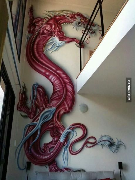 a large red dragon painted on the side of a white wall next to a bed