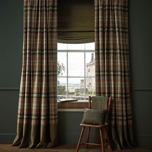 a chair sitting in front of a window next to a wooden stool with a pillow on it