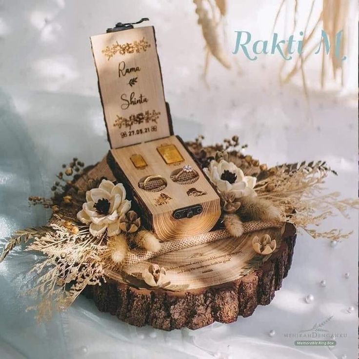 an image of a wooden box with rings on it and flowers in the middle, sitting on top of a piece of wood