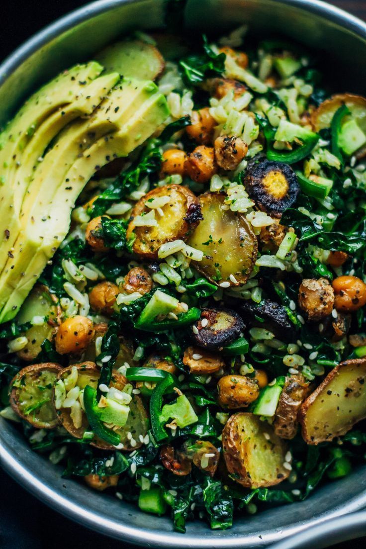 a bowl filled with vegetables and avocado on top of a table