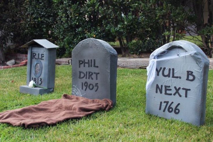 three cement headstones with the names phil, dirt next to them on grass in front of trees