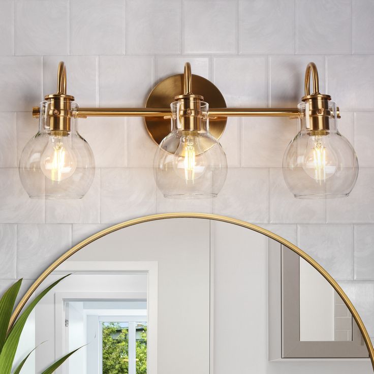 a bathroom vanity light with three bulbs on the side and a round mirror above it