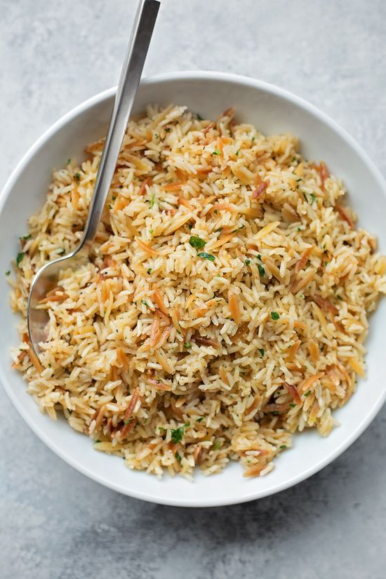 a white bowl filled with rice on top of a gray counter next to a silver spoon