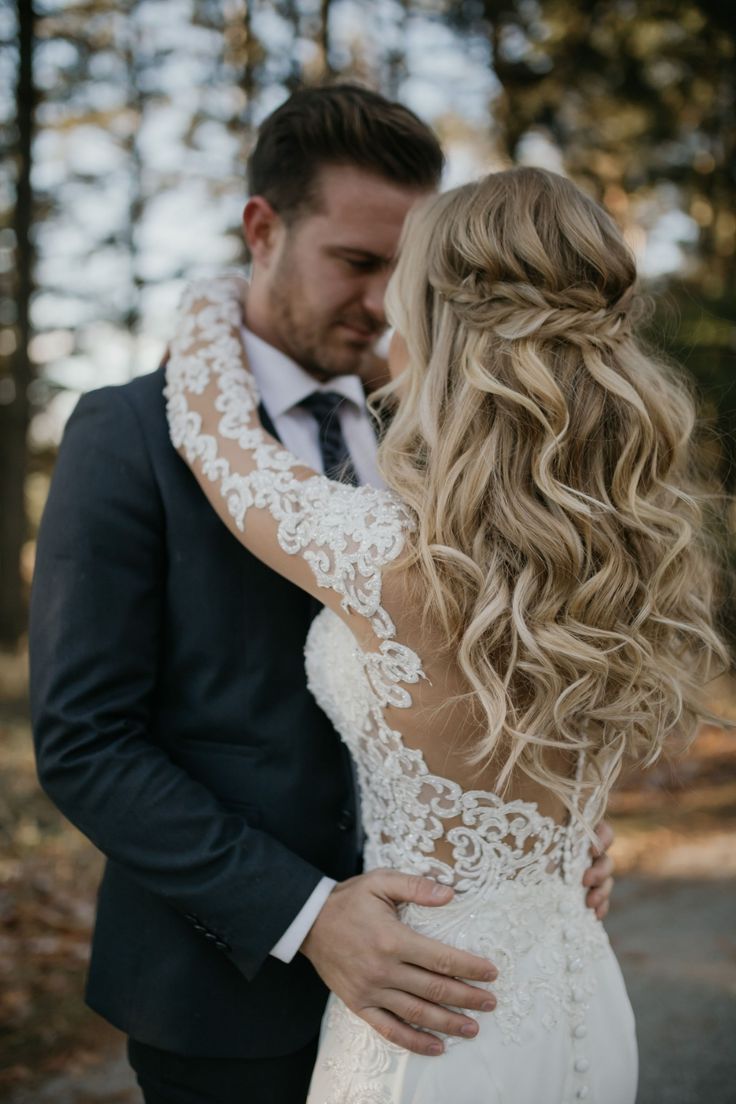 a bride and groom embracing each other in the woods