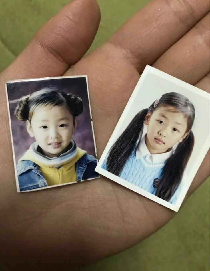 two small pictures of children in the palm of someone's hand