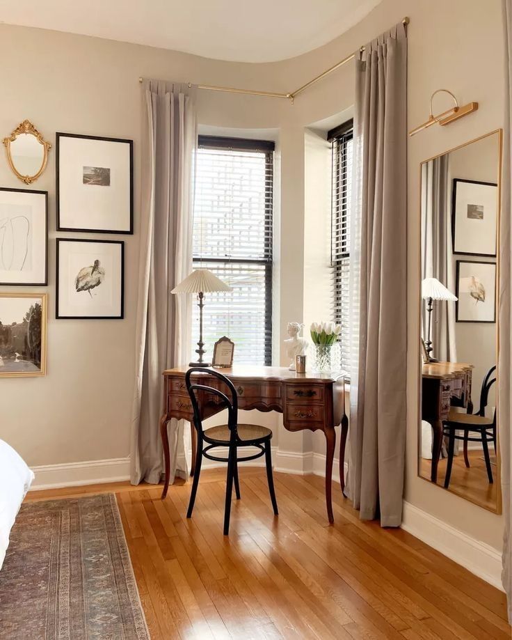 a bedroom with a desk, mirror and pictures on the wall