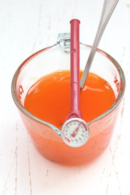 a measuring cup filled with orange liquid and a spoon