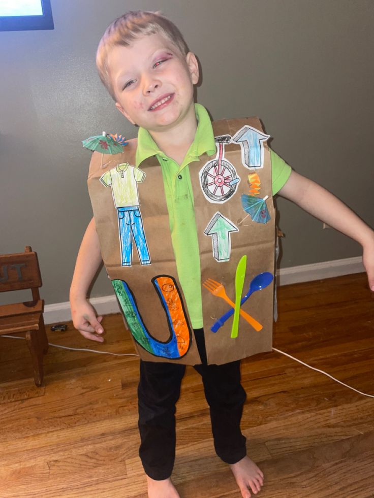 a young boy wearing a cardboard costume made to look like he is holding a paper bag with magnets on it