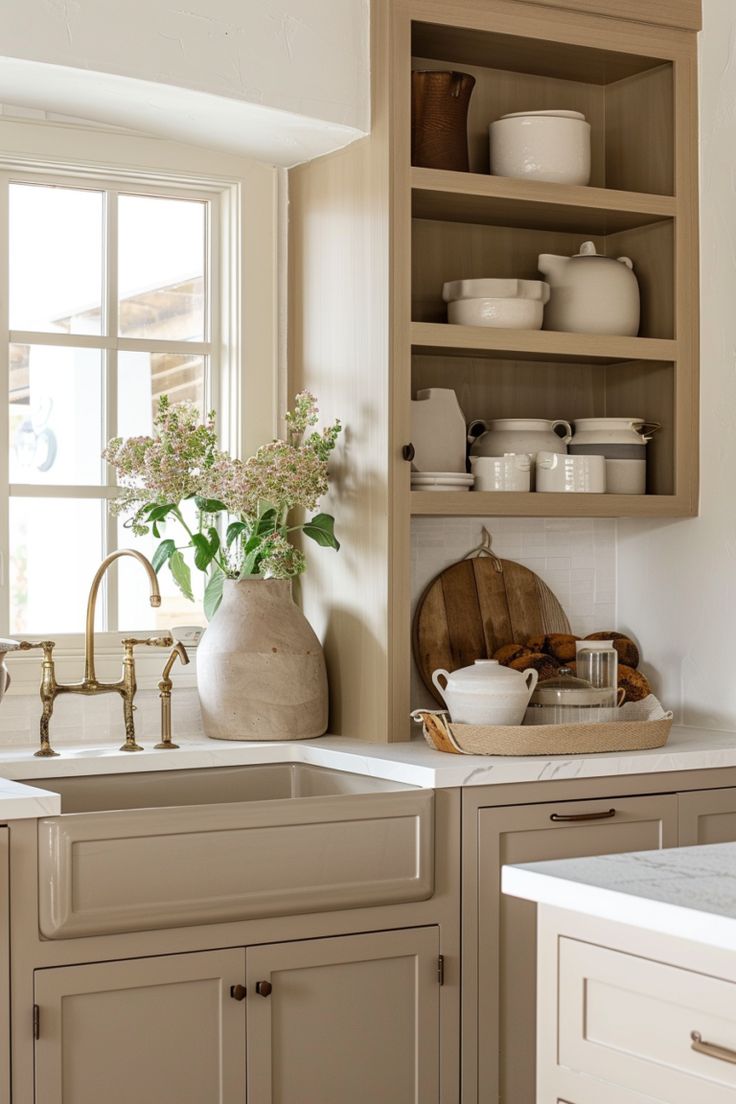 a white kitchen with wooden cabinets and open shelving above the sink is filled with dishes