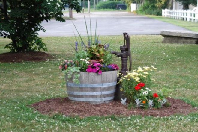 a wooden barrel filled with flowers next to a bench