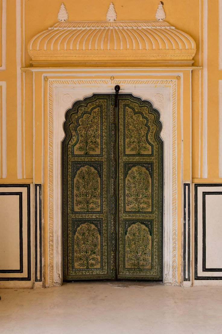 an ornately decorated door in the middle of a yellow and white building with black trim