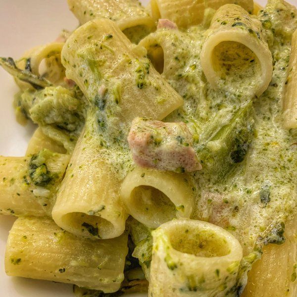 a white plate topped with pasta covered in pesto