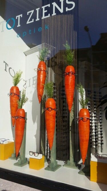 a store front window with carrots on display in it's windows displays glasses and plants