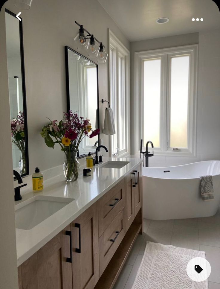 a large bathroom with two sinks and a bathtub in the middle, along with mirrors on the wall