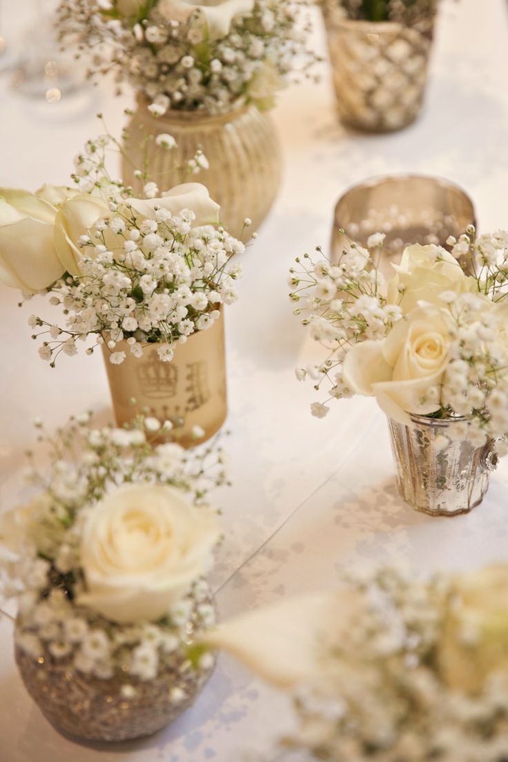 there are many small vases with flowers in them on the tablecloth, and one is filled with baby's breath