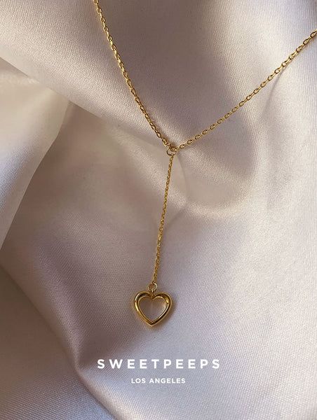 Product Details + Care  - 18K Gold Dipped Over Brass - Brass: Copper + Zinc Alloy - 1 Necklace - Wipe Clean  - Imported  Dimensions - Chain Approximately 16" Have a question? Please message info@shopsweetpeeps.com and our support team will get back to you in 48 hours. Gold Heart Dangle Necklace With Adjustable Chain, Heart-shaped Lariat Necklace With Clavicle Chain, Adjustable Gold Heart Necklace With Clavicle Chain, Gold Heart Charm Lariat Necklace, Gold Lariat Jewelry With Heart Charm, Gold Lariat Necklace With Heart Charm, Heart Pendant Lariat Necklace For Valentine's Day, Valentine's Day Jewelry With Adjustable Dangle Chain, Valentine's Day Dangle Jewelry With Adjustable Chain