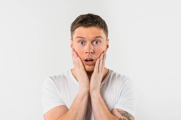 a man holding his hands to his face while looking at the camera with an surprised look on his face