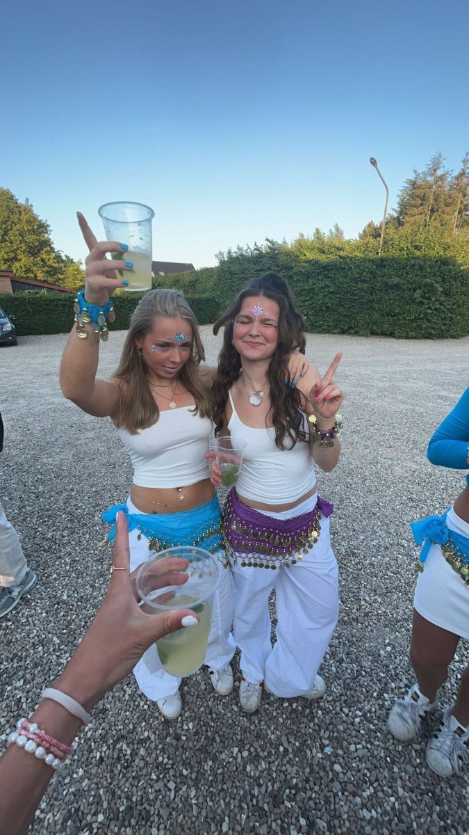 two women in white shirts and blue shorts are holding up their hands while posing for the camera