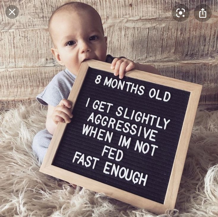 a baby holding a sign that says, 8 months old i get slightly aggressive when i'm not fed enough