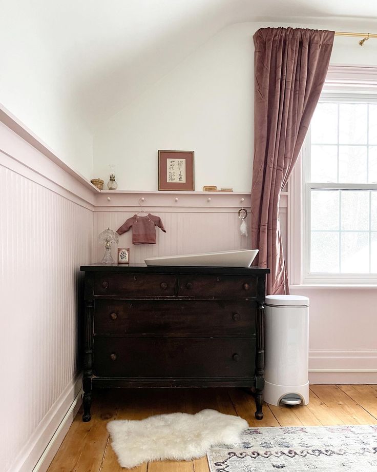 a baby's crib in the corner of a room with pink walls and wood floors