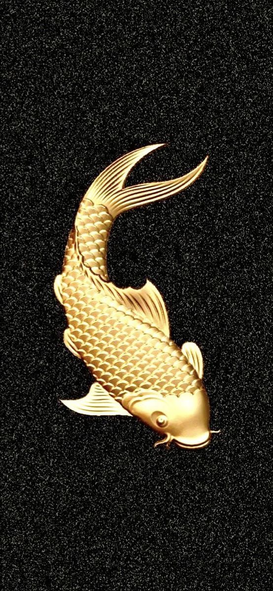 a gold fish on a black surface with its tail curled in the shape of a wave