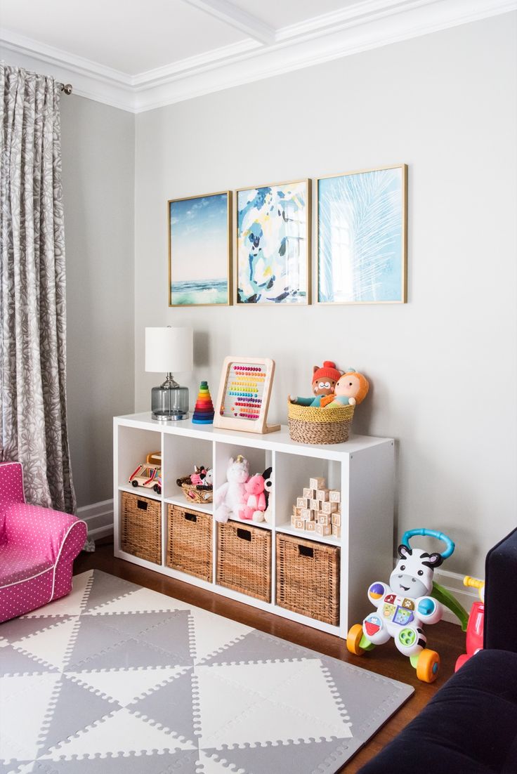 a child's room with toys and decor on the wall, including a pink chair