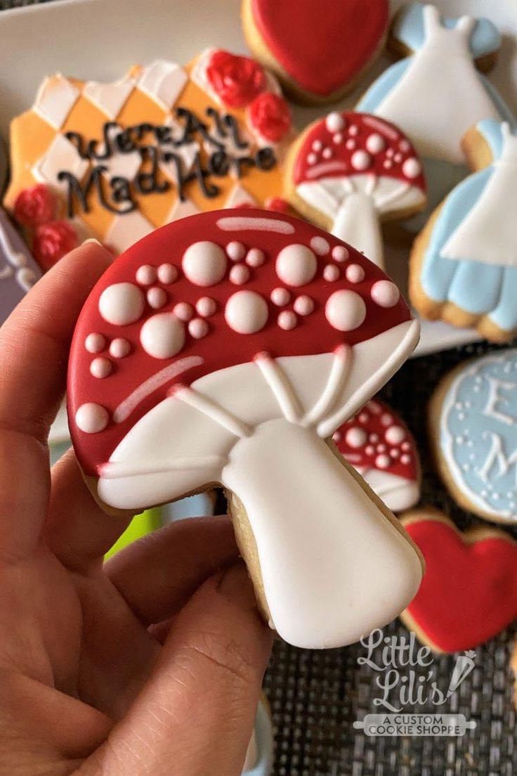 a hand holding a decorated cookie in front of some cookies