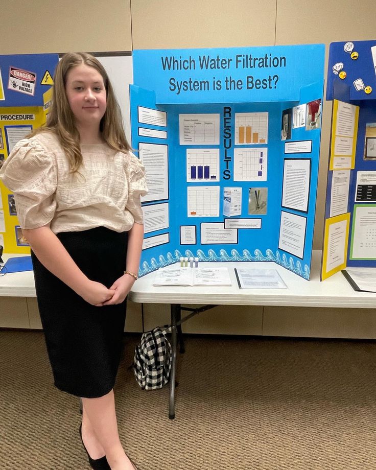 a girl standing in front of a poster board with information about water filtrator systems