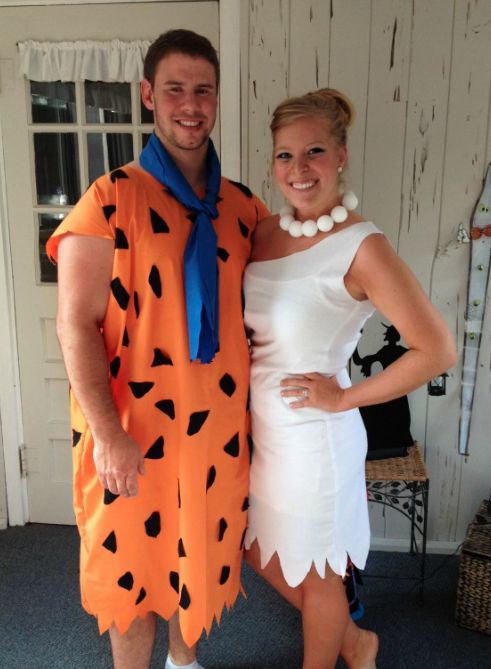 a man and woman dressed up as flint and the flintstones, standing next to each other