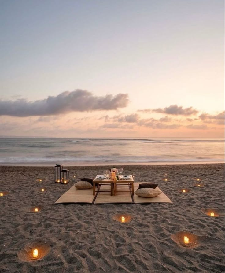 a table set up on the beach with candles