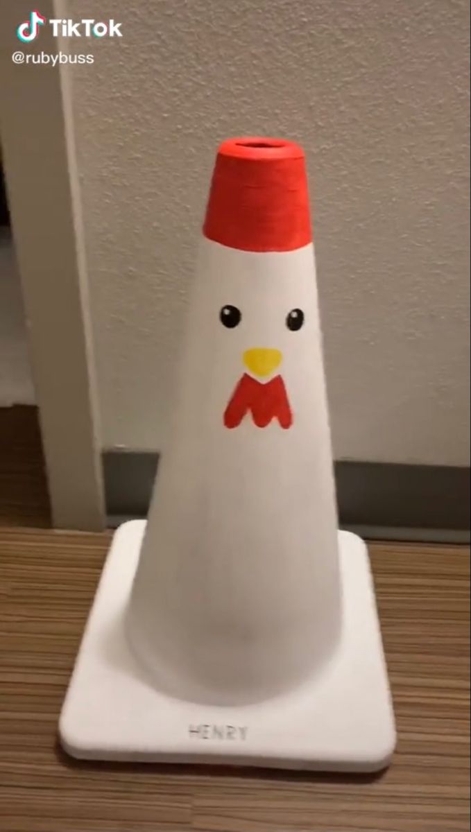 a white plastic cone with a red top on a wooden table next to a wall