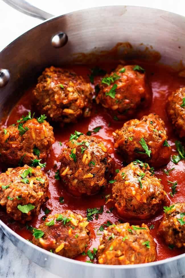 meatballs with tomato sauce and parsley on a white plate, ready to be eaten