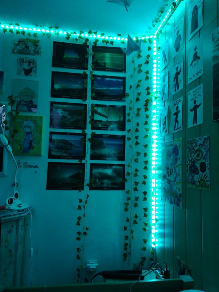 a bedroom with green lights on the wall and pictures hanging up against the wall behind it