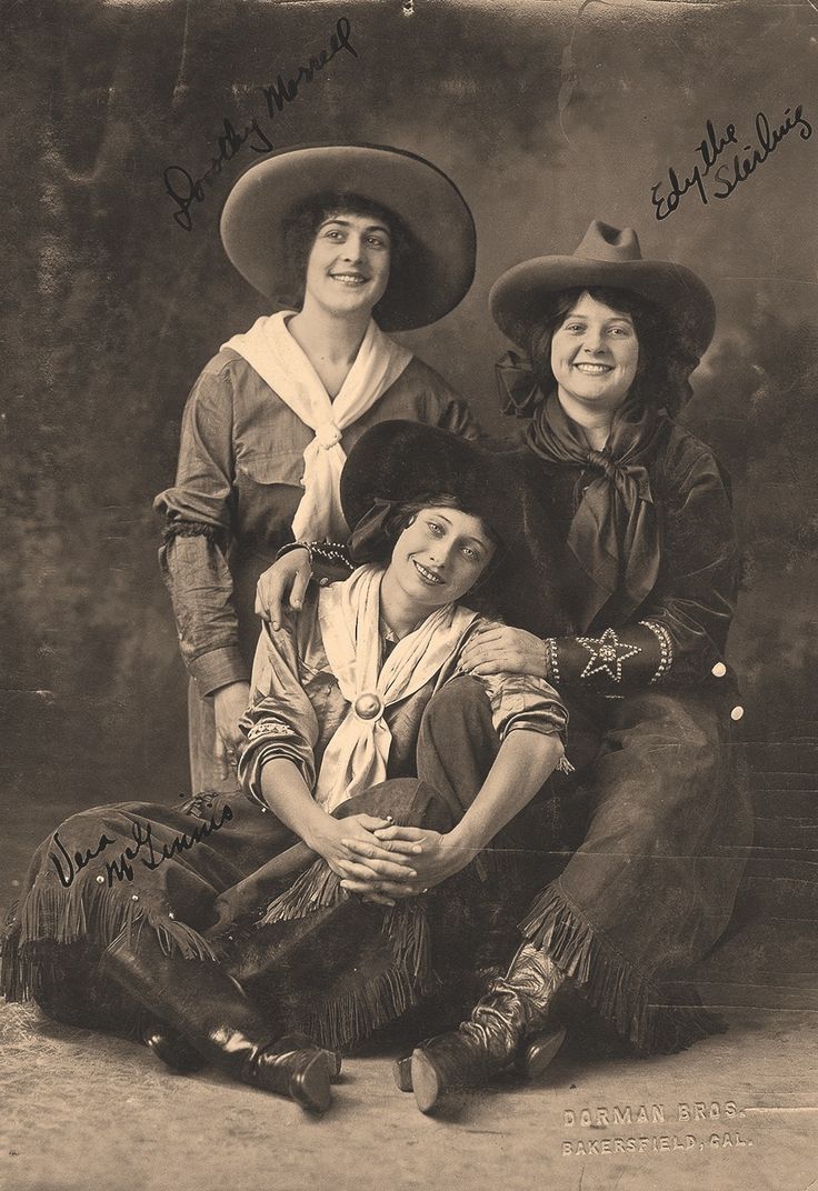 an old photo of two women in cowboy hats posing for a picture with another woman sitting on the ground