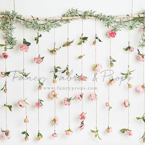 the wall is decorated with pink flowers and greenery hanging from it's sides