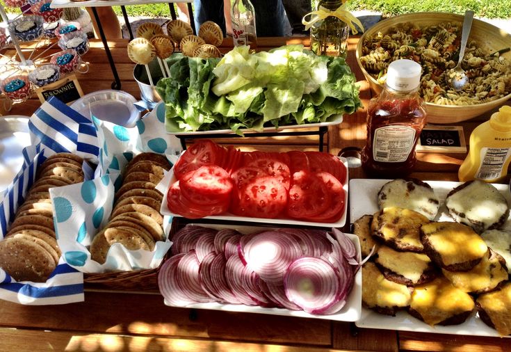 an assortment of food is displayed on a picnic table with blue and white striped napkins