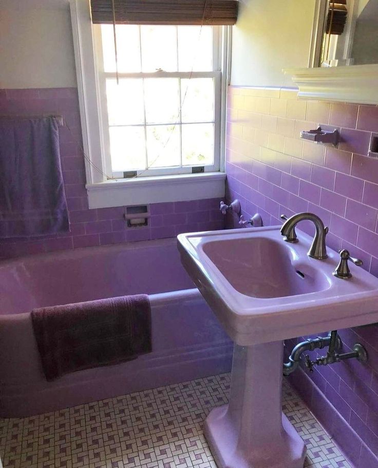 a bath room with a sink a tub and a window in it's corner