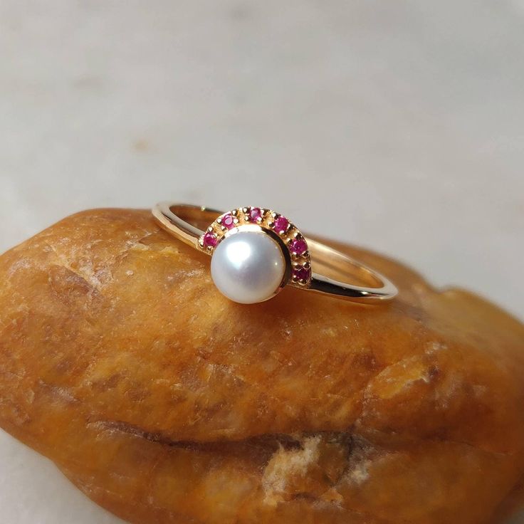 This stunning ring is set in 14k Solid Yellow Gold with Natural Pear & Ruby with utmost precision. It is an unique statement gemstone ring for nearly every occasion and is completely hassle-free jewelry. ITEM DETAILS: * Gem: Pearl * Gem Size: 5mm * Gem Shape: Round * Gem: Ruby * Gem Size: 1mm * Gem Shape: Round * Gem weight: 0.81 carats * Gold Purity: 14KT  * Gold Weight: 1.49 gram * Total Weight of the Ring: 1.65 gram The Gold purity is guaranteed and it comes with an authentic 14KT gold hallma Timeless Ruby Ring With Halo Setting As A Gift, Timeless White Sapphire Ring Gift, 14k Gold Pearl Ring With Gemstone, White Ruby Rings Fine Jewelry, Elegant Ruby Halo Ring Gift, Elegant White Ruby Promise Ring, Luxury Pearl Ring With Round Band As Gift, White Round Ruby Ring In Fine Jewelry Style, White Ruby Ring In 14k Gold