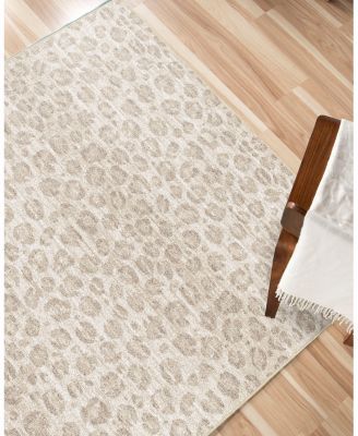 a white rug with an animal print pattern on the top and bottom, in front of a wooden floor