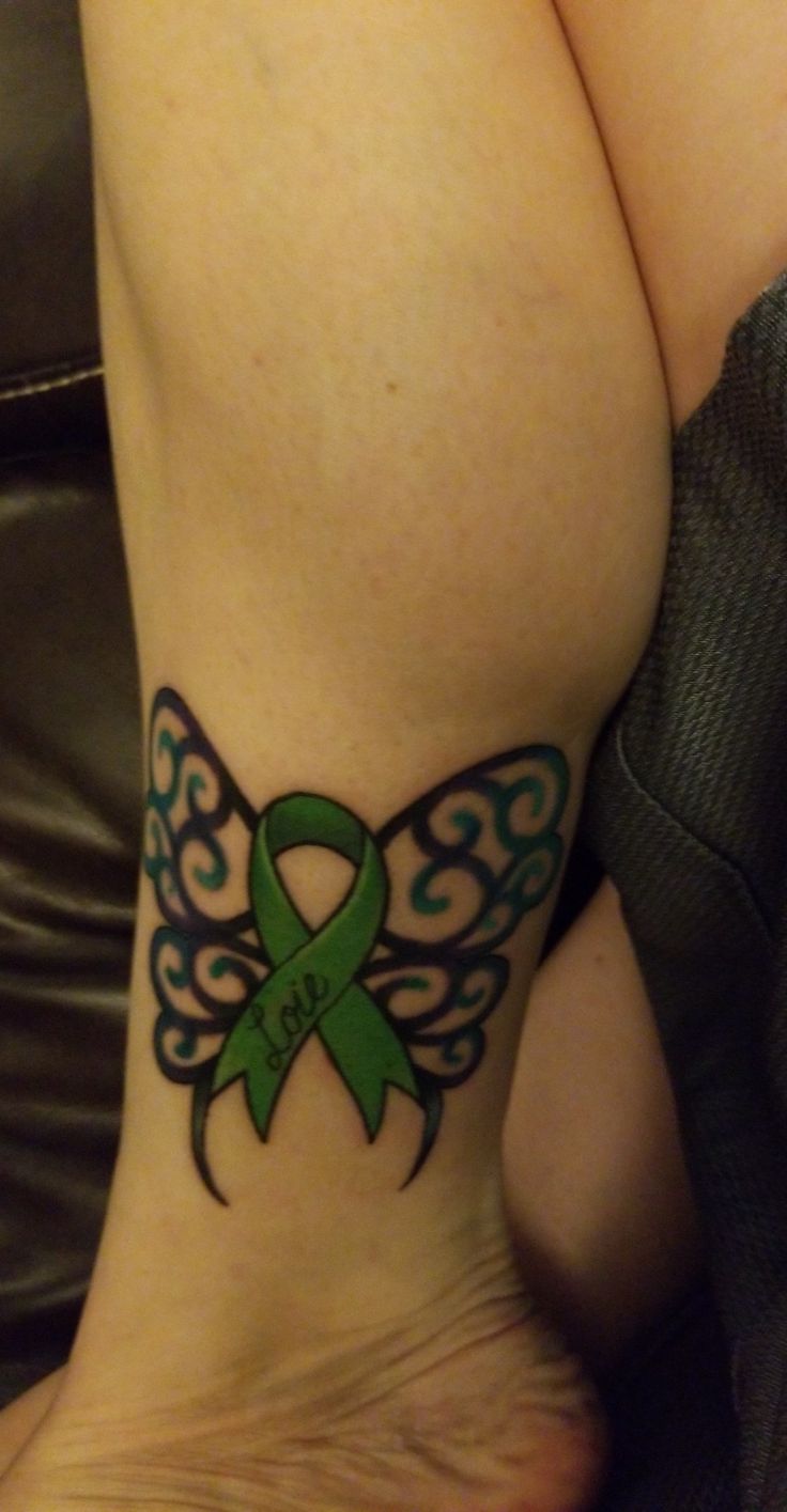 a woman with a green ribbon tattoo on her leg