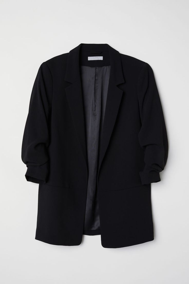 a black blazer jacket hanging on a wall with the back button down and buttons undone