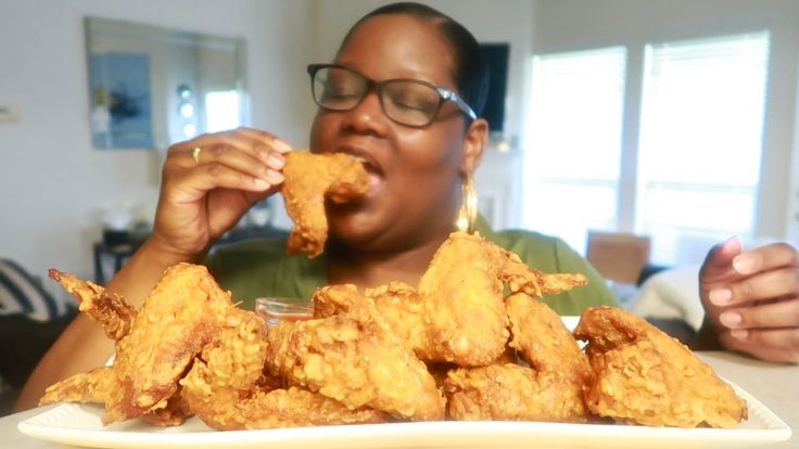 a woman sitting at a table eating fried food