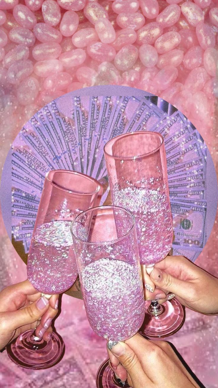 three people holding up wine glasses in front of a pink background with beads and sequins