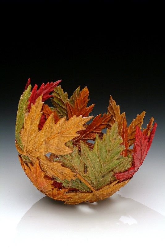 a glass bowl filled with leaves on top of a table