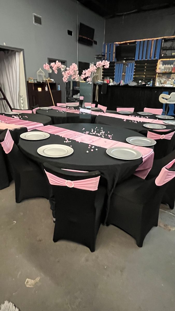 the tables are set up with black and pink linens