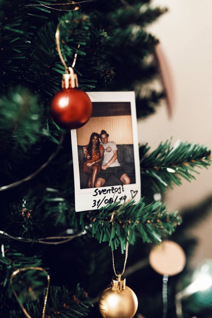 an ornament hanging from a christmas tree with a photo on it's side