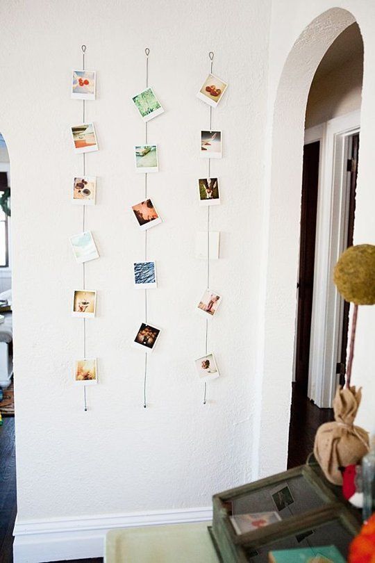 there are many pictures hanging on the wall with clothes pins attached to them, along with other things