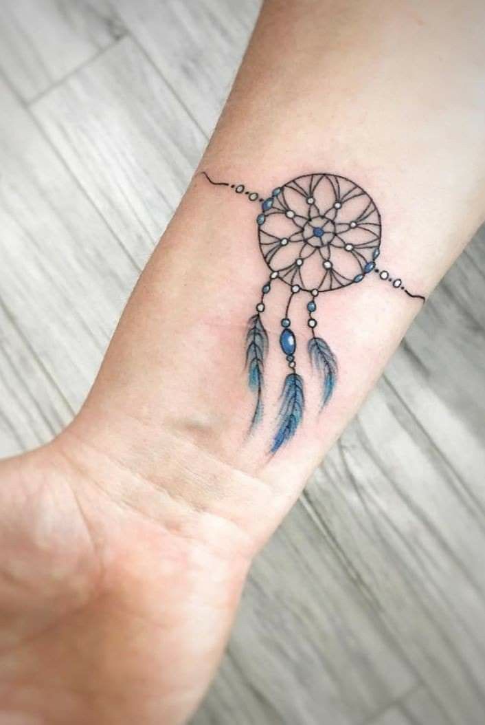 a small wrist tattoo with a dream catcher on it